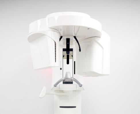 Dental panoramic X-ray machine positioned against white background, professional dental imaging equipment.