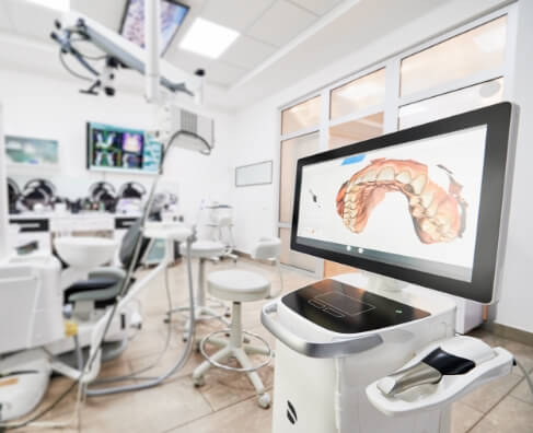 Modern dental office with surgical microscope and digital display showing dental imaging scan.