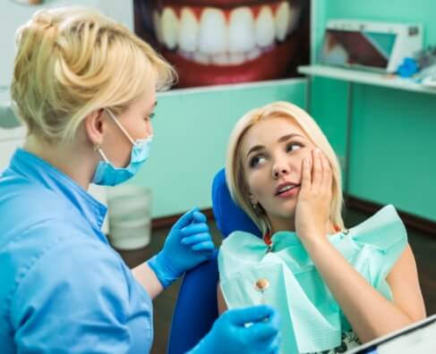 Dental hygienist examining patient's teeth in bright clinical treatment room at Breezy Point Smiles.
