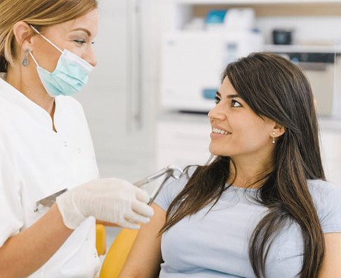 Healthcare professional administering vaccine to young woman in medical clinic setting.