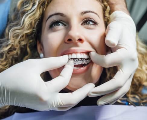Dentist examining patient's teeth during dental checkup with gloved hands.