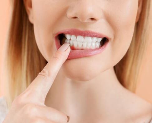 Woman pointing to her white teeth while smiling, demonstrating dental health and smile care.
