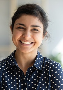 Smiling woman in polka dot shirt against white background, professional headshot for dental practice.