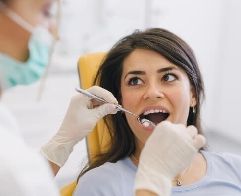 Woman receiving dental examination in dentist's chair at Breezy Point Smiles office.