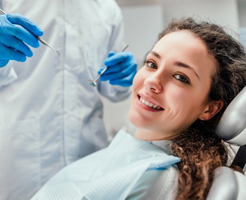 Young woman smiling at dentist during dental examination in clinical office setting.