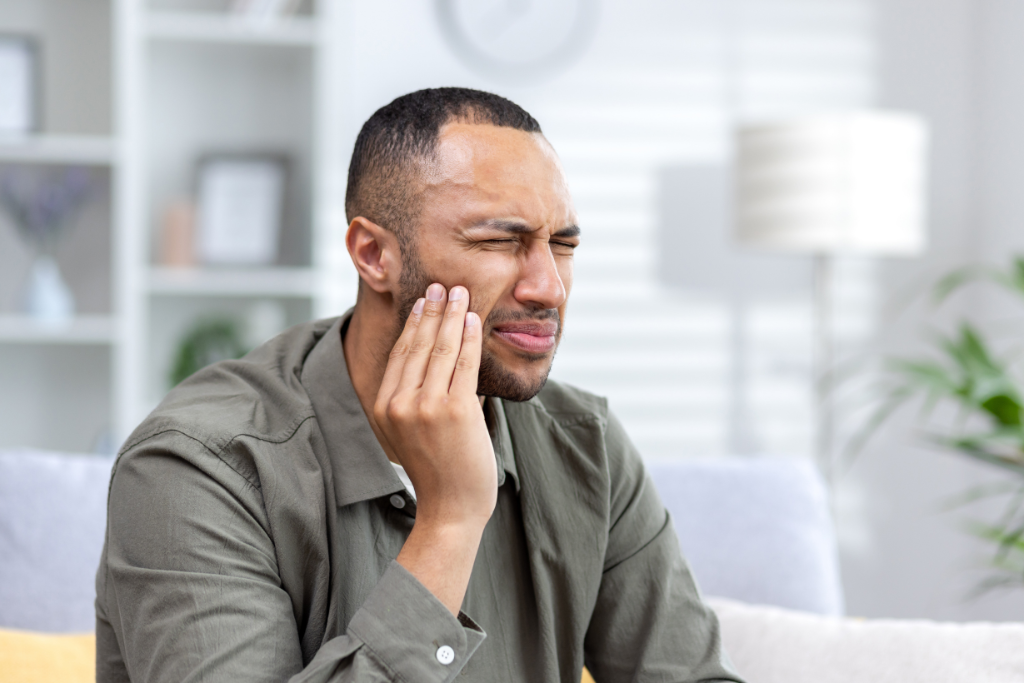 Man wincing while holding his cheek