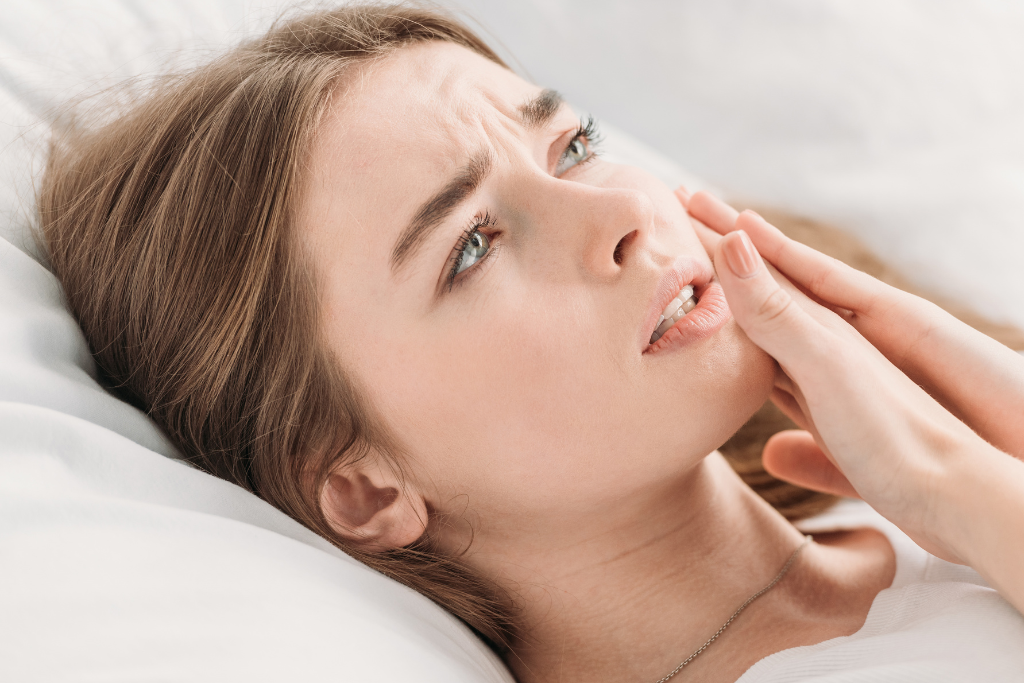 Woman looking up with hand near her jaw in discomfort