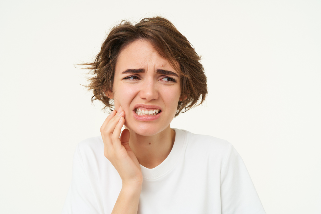 Woman wincing and holding her cheek in pain