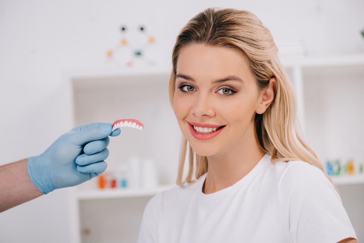 Cosmetic dentist showing a dental model to a woman during treatment consultation
